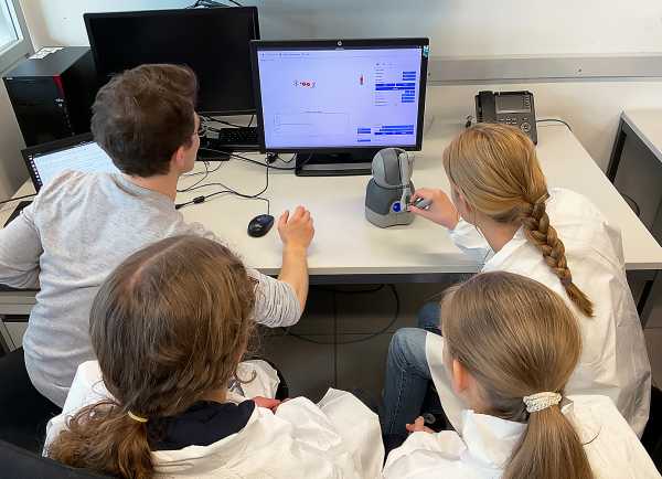 School students working with the haptic device and feeling the force acting on the atoms (Photo: J.Ecker)
